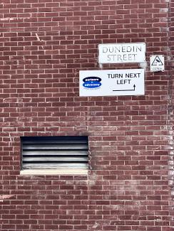 Red bricks, grille and scruffy signs on Dunedin Street.