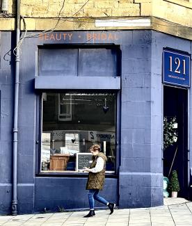 Person in blue jeans walking past blue frontage of bridal wear shop at corner of Beaverhall and Broughton Roads.