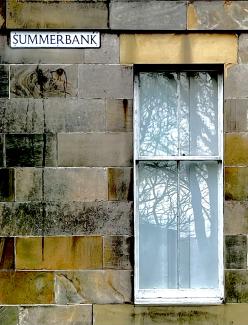 Summerbank street sign, with colourful masonry and a domestic window reflecting trees.