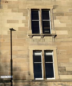 Lamppost shadow on Eyre Place wall resembling a giraffe's neck and head.
