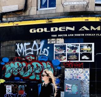 Woman walking past graffiti underneath Albert Street street-name sign.