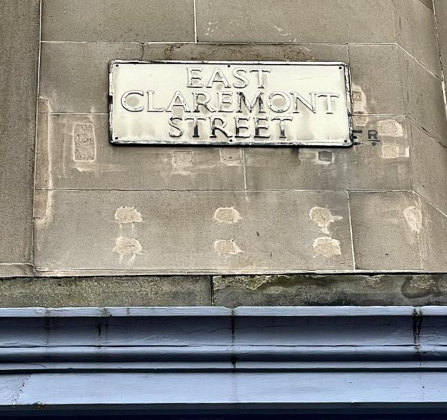 Black letters reading ER, painted directly onto the masonry. A more recent sign for EAST CLAREMONT STREET obscures the rest of the name.